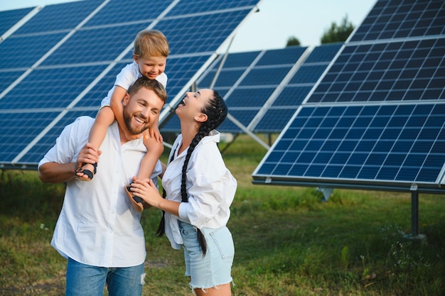 Jeune famille avec un petit enfant dans les bras sur fond de panneaux solaires Un homme et une femme se regardent avec amour Concept d'énergie solaire