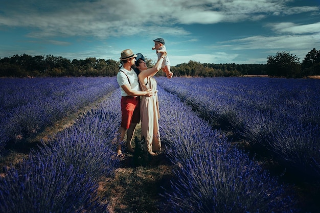 Jeune famille avec un petit enfant posant dans un champ de lavande