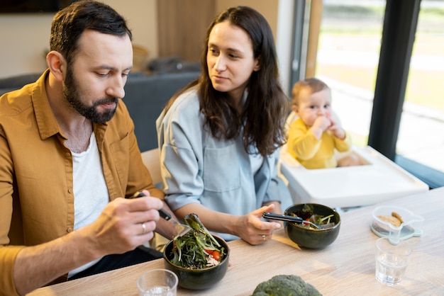 Jeune famille avec un petit garçon d'un an pendant l'heure du déjeuner à la maison