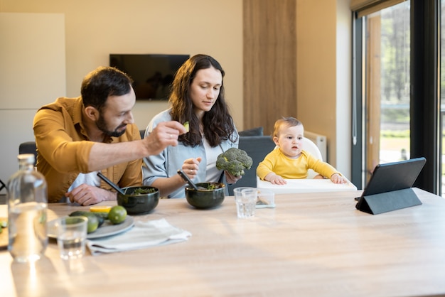 Jeune famille avec un petit garçon d'un an pendant l'heure du déjeuner à la maison