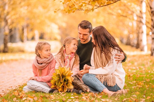 Jeune famille avec petits enfants dans le parc d'automne aux beaux jours. Portrait d'automne de famille