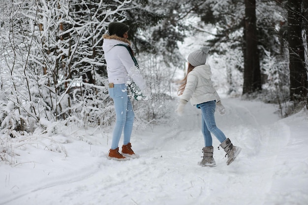 Jeune famille pour une promenade. Maman et sa fille marchent dans un parc d'hiver.