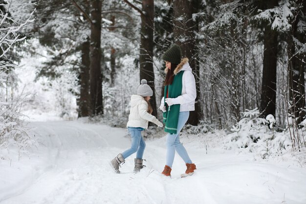 Jeune famille pour une promenade. Maman et sa fille marchent dans un parc d'hiver.