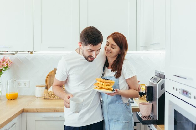 Jeune famille prépare le petit déjeuner ensemble, mari et femme heureuse