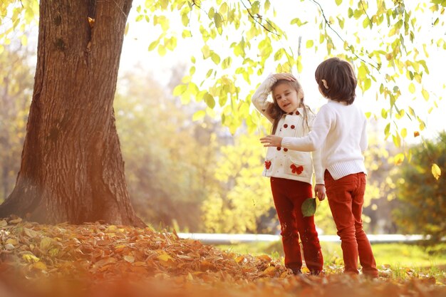 Jeune famille en promenade dans le parc en automne par une journée ensoleillée. Le bonheur d'être ensemble.