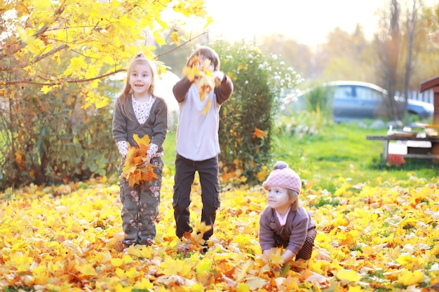 Jeune famille en promenade dans le parc en automne par une journée ensoleillée. Le bonheur d'être ensemble.