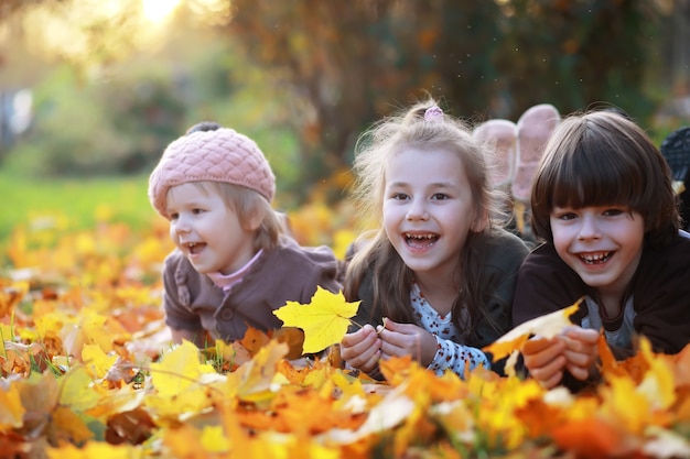 Jeune famille en promenade dans le parc en automne par une journée ensoleillée. Le bonheur d'être ensemble.