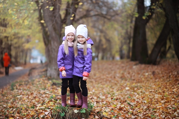 Jeune famille en promenade dans le parc en automne par une journée ensoleillée. Le bonheur d'être ensemble.