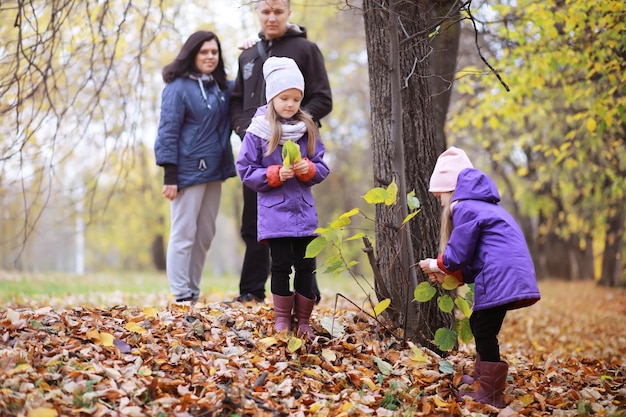 Jeune famille en promenade dans le parc en automne par une journée ensoleillée. Le bonheur d'être ensemble.