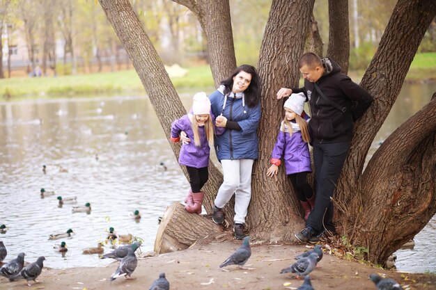 Jeune Famille En Promenade Dans Le Parc En Automne Par Une Journée Ensoleillée. Le Bonheur D'être Ensemble.