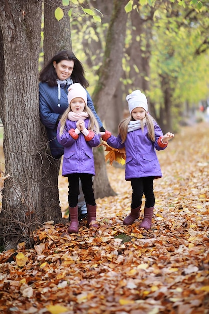 Jeune famille en promenade dans le parc en automne par une journée ensoleillée. Le bonheur d'être ensemble.