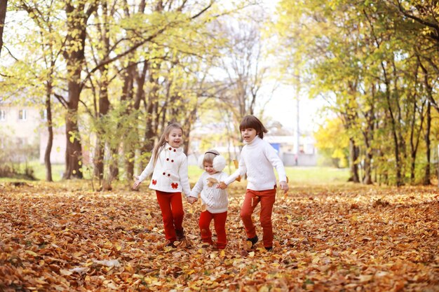 Jeune famille en promenade dans le parc en automne par une journée ensoleillée. Le bonheur d'être ensemble.