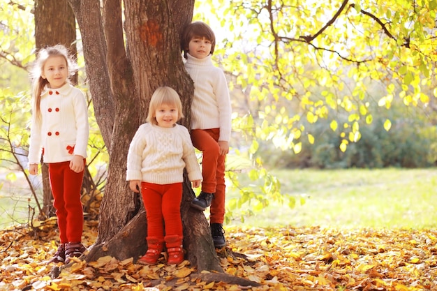 Jeune famille en promenade dans le parc en automne par une journée ensoleillée. Le bonheur d'être ensemble.