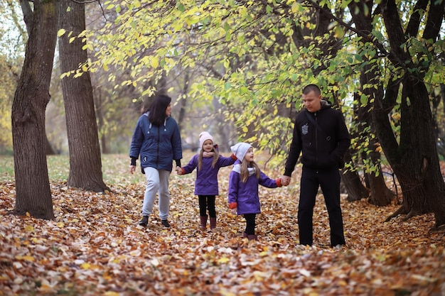 Photo jeune famille en promenade dans le parc en automne par une journée ensoleillée. le bonheur d'être ensemble.