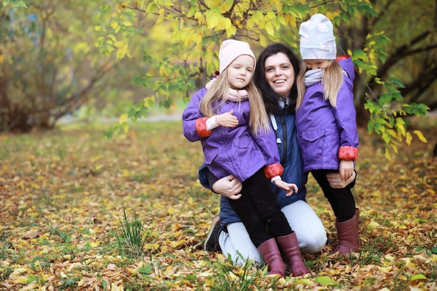 Jeune famille en promenade dans le parc en automne par une journée ensoleillée. Le bonheur d'être ensemble.