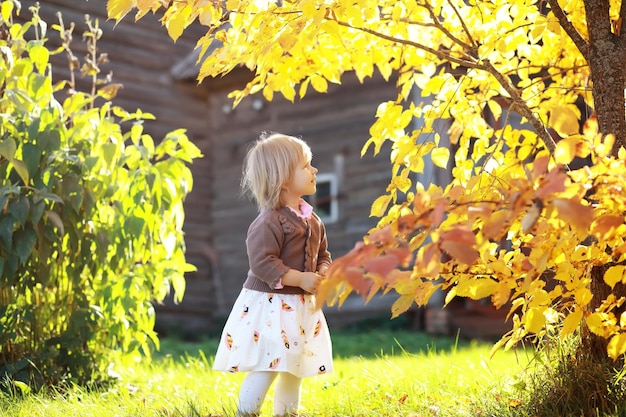 Jeune famille en promenade dans le parc en automne par une journée ensoleillée. Le bonheur d'être ensemble.