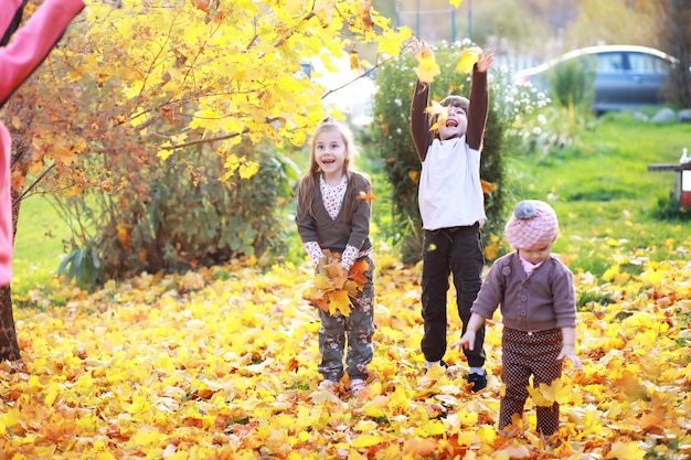 Jeune famille en promenade dans le parc en automne par une journée ensoleillée. Le bonheur d'être ensemble.