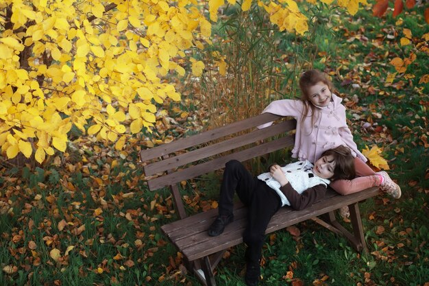 Jeune famille en promenade dans le parc en automne par une journée ensoleillée. Le bonheur d'être ensemble.