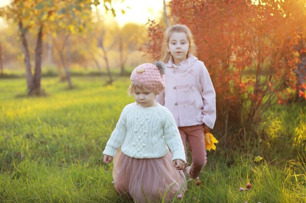 Jeune famille en promenade dans le parc en automne par une journée ensoleillée. Le bonheur d'être ensemble.