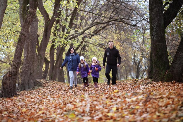 Jeune famille en promenade dans le parc en automne par une journée ensoleillée. Le bonheur d'être ensemble.