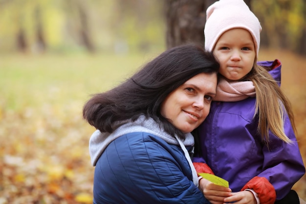 Jeune famille en promenade dans le parc d'automne par une journée ensoleillée Bonheur d'être ensemble