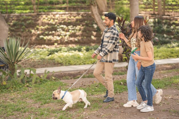 Jeune famille promener le chien dans un parc