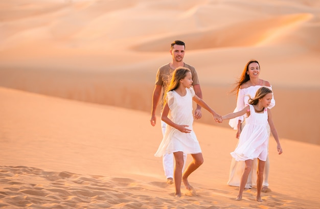 Jeune famille de quatre personnes dans le grand désert de sable