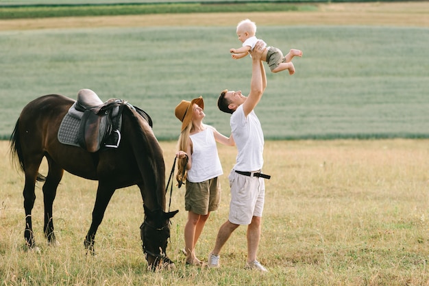 Une jeune famille s&#39;amuse dans le domaine. Parents et enfant avec un cheval