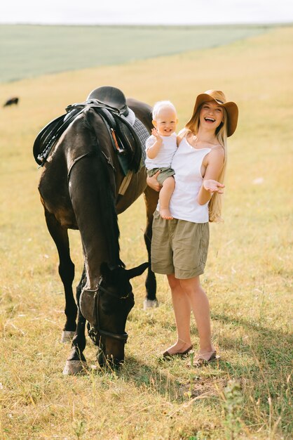 Une jeune famille s&#39;amuse dans le domaine. Parents et enfant avec un cheval