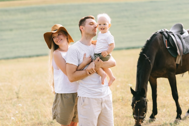 Une jeune famille s&#39;amuse dans le domaine. Parents et enfant avec un cheval