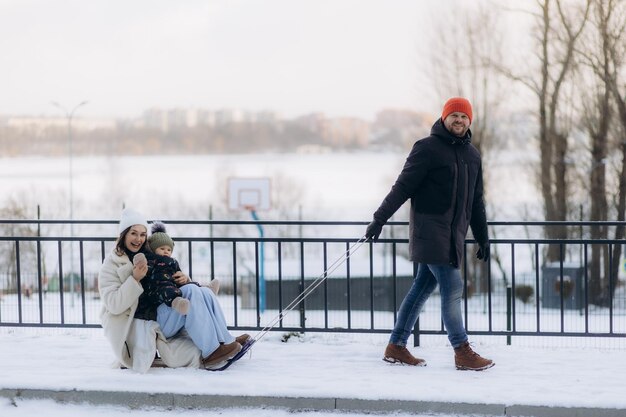Une jeune famille s'amuse à faire du traîneau en hiver.