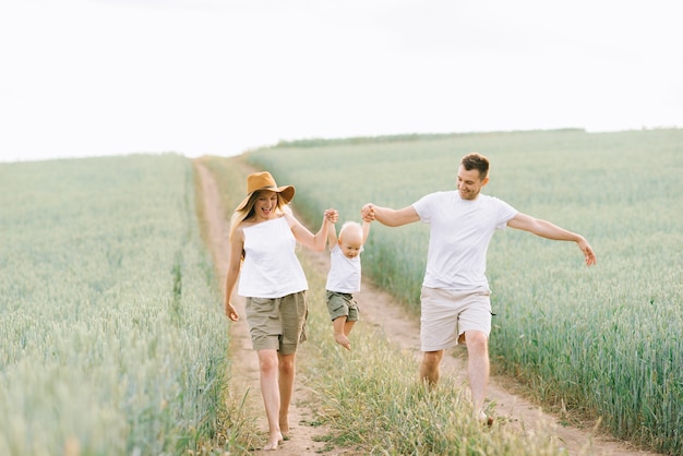 Une jeune famille s&#39;amuse avec leur petit bébé dans le champ