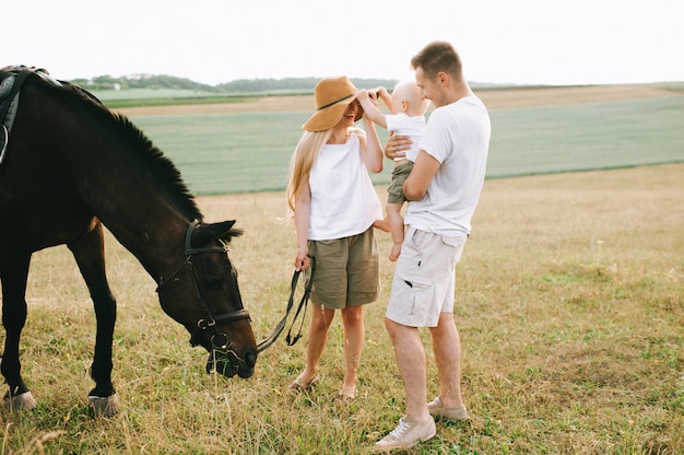 Une jeune famille s'amuse sur le terrain. Parents et enfant avec un cheval