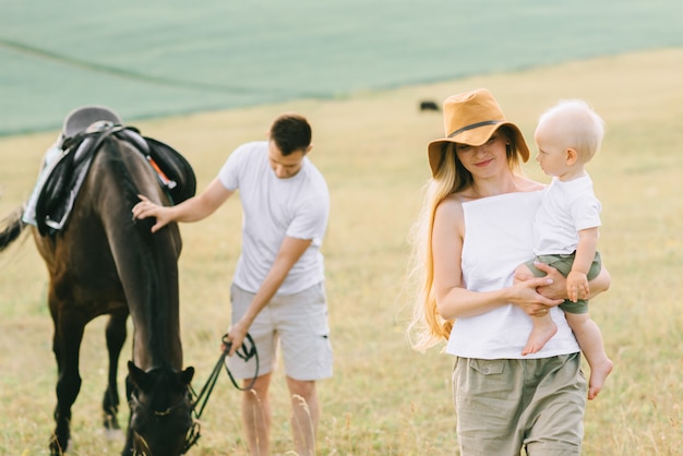 Une jeune famille s'amuse sur le terrain. Parents et enfant avec un cheval