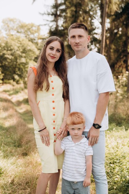 Une jeune famille se promène dans un parc de conifères et passe du temps ensemble