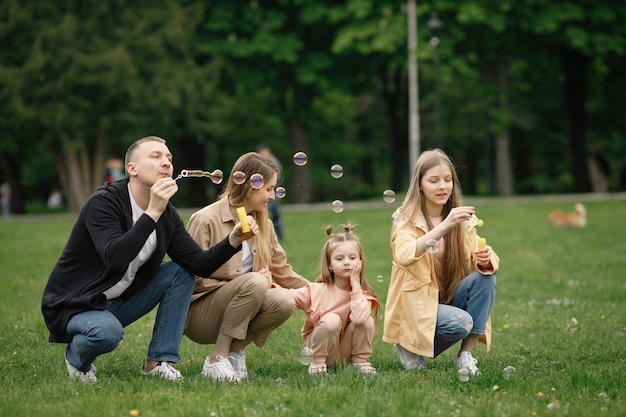 Jeune famille soufflant des bulles de savon en marchant dans le parc