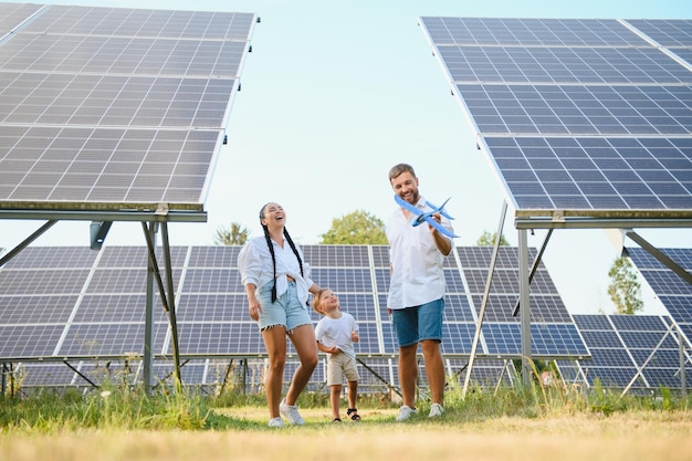 Une jeune famille de trois personnes est accroupi près d'un panneau solaire photovoltaïque petit garçon et ses parents concept de famille moderne le concept d'énergie verte