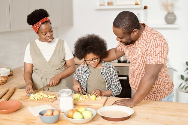 Jeune famille de trois personnes préparant le petit déjeuner par table de cuisine