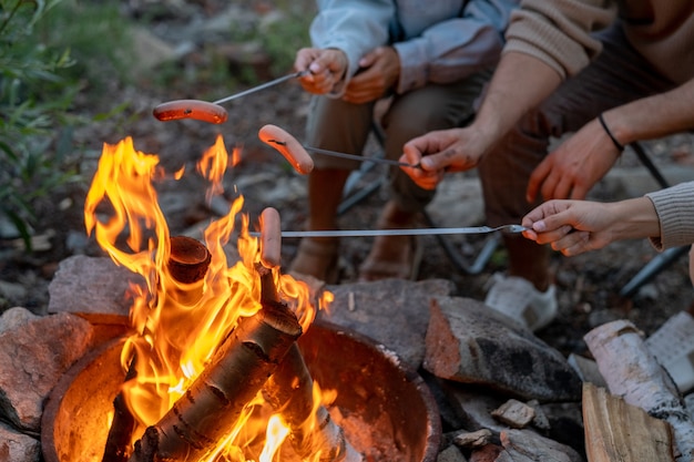 Jeune famille de trois saucisses de cuisson sur feu de camp