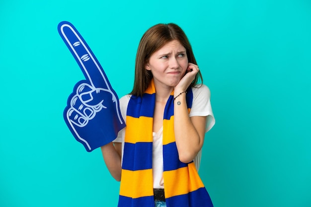 Jeune fan de sport femme isolée sur fond bleu frustré et couvrant les oreilles