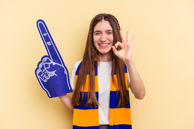 Jeune fan de sport femme isolée sur fond jaune gaie et confiante montrant un geste ok