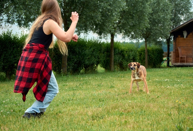 Une jeune femelle jouant avec son beau chien brun dans le jardin