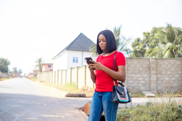 Jeune femme de 20 ans commandant un taxi via l'application de cabine sur smartphone en se tenant debout dans la rue