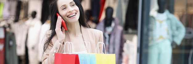 Jeune femme accro du shopping souriant et dit à un ami sur appel au sujet des ventes