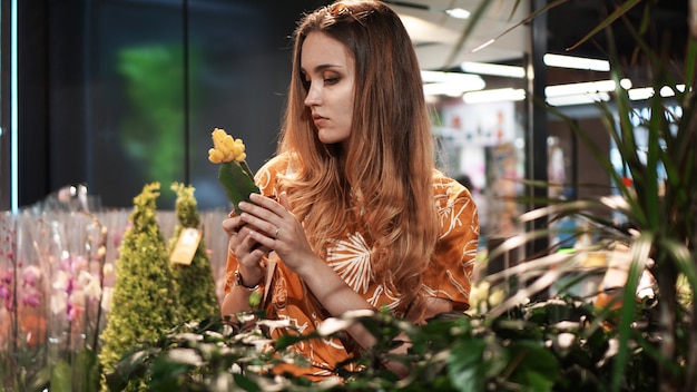 Jeune femme achetant des fleurs dans un pot dans un centre de jardinage