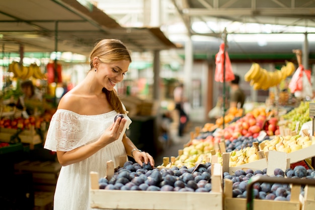 Jeune femme achetant des fruits sur le marché