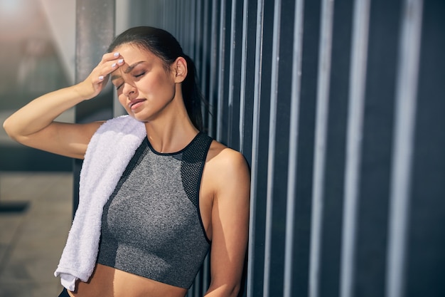 Jeune femme active s'appuyant sur le mur tout en faisant face, ayant des maux de tête