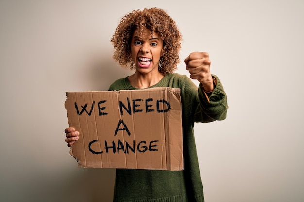 Jeune femme activiste afro-américaine demandant le changement tenant une bannière avec un message agacé et frustré criant de colère folle et criant avec le concept de colère de la main levée