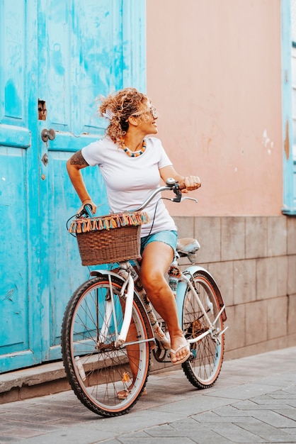 Photo jeune femme adulte aime faire du vélo seule dans la rue maison de la porte bleue en arrière-plan femme regardant en arrière et faire du vélo seul printemps activité de loisirs en plein air personnes et concept de transport