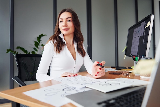 La jeune femme adulte dans des vêtements formels est à l'intérieur dans le bureau